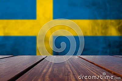 Wood Table Top and Grunge Sweden Flag on concrete wall. Stock Photo