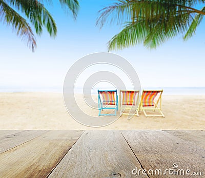 Wood table top on blur beach background with beach chairs under coconut tree Stock Photo