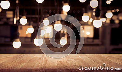 Wood table top on blurred of counter cafe shop with light bulb background Stock Photo