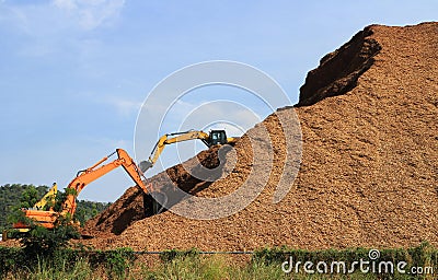 Woodchip Mountain with Backhoes working Stock Photo