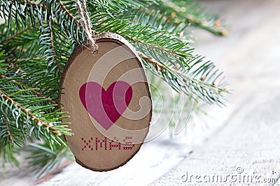 Wooden adornment with heart and xmas inscription hanging on christmas tree Stock Photo