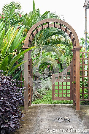 Wooden arbor with close on half gate in garden. Wooden arched entrance to the backyard. Stock Photo