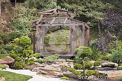 Wooden arbor surrounded by bonsai trees, pines in a Japanese stone garden Stock Photo