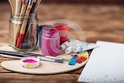 Wooden art palette with tubes of oil paints and a brush. Art and craft tools. Artist`s brush, canvas, palette knife. Space for tex Stock Photo