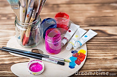 Wooden art palette with tubes of oil paints and a brush. Art and craft tools. Artist`s brush, canvas, palette knife. Space for tex Stock Photo