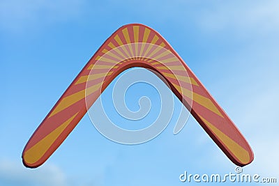 Wooden australian boomerang in flight against of pure white clouds and blue sky Stock Photo