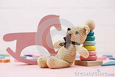 Wooden baby toys on a pastel pink background. numbers, blocks, puzzle shapes, rainbow. Set of accessories for children. Stock Photo