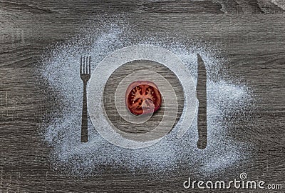 On a wooden background flour powder powdered snow silhouette plate plate fork knife appliances lies a round slice of tomato Stock Photo