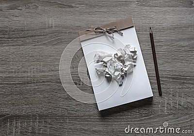 On a wooden background lies a craft notepad scrapbooking pencil on a notepad heart of crumpled paper Stock Photo