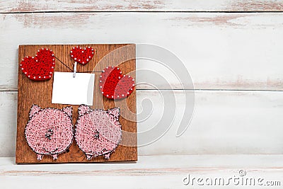 On a wooden background there is a handmade panel with the image of two pigs and hearts . copy space Stock Photo