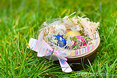 Wooden basket with colorful Easter eggs and flowers Stock Photo