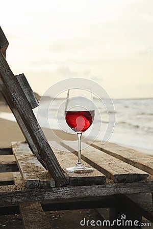 Wooden bench with glass of wine on sandy sea beach Stock Photo