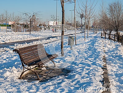 Wooden bench located on a snowy walk Stock Photo