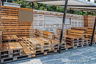 Wooden bench made of pallets of freight cargo cases for sitting. Creative outdoor cafe table and benches. Conceptual chairs and Stock Photo