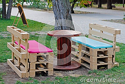 Wooden bench made of pallets for sitting with table made from coil of electric cable Stock Photo