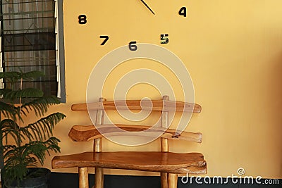 Wooden bench near yellow wall. Vintage wooden bench under the wall clock Stock Photo