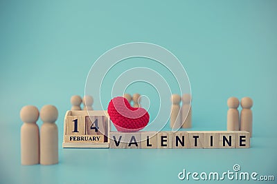 A wooden block with a message written on 14 FEB representing Valentine`s Day with red heart on blocks wood and many couples on Stock Photo