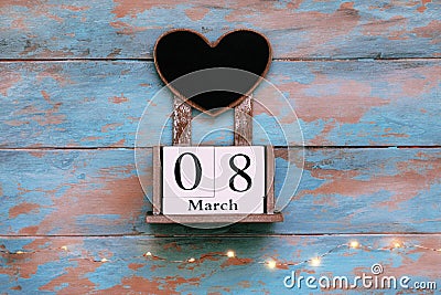 Wooden block save the date calendar, March 8, with heart shaped chalk board on vintage blue background with garland Stock Photo