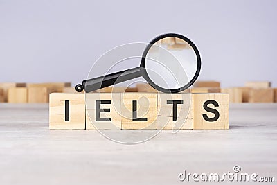 Wooden blocks with a magnifying glass text: IELTS. International English Language Testing System Stock Photo