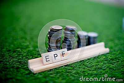 Wooden blocks spelling EPF with a stack of coins growing in size set on grass Stock Photo