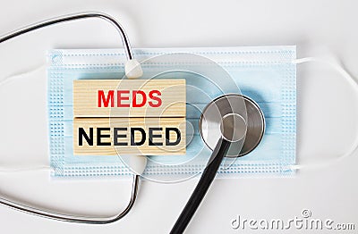 Wooden blocks with text Meds Nedded lying on the mask and a stethoscope Stock Photo