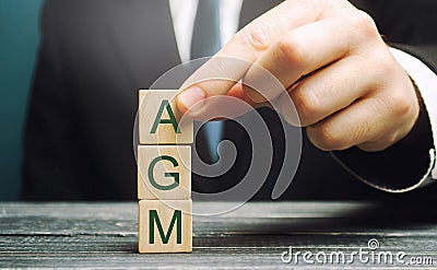 Wooden blocks with the word AGM - Annual general meeting. Mandatory yearly gathering of a company`s interested shareholders. Stock Photo