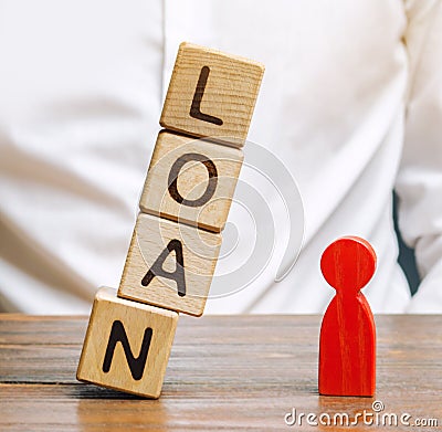 Wooden blocks with the word Loan fall on a miniature person. The concept of large lending rates for property and business. Lending Stock Photo