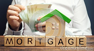 Wooden blocks with the word Mortgage and money in the hands of a businessman. The concept of buying a home on credit. Loan for Stock Photo