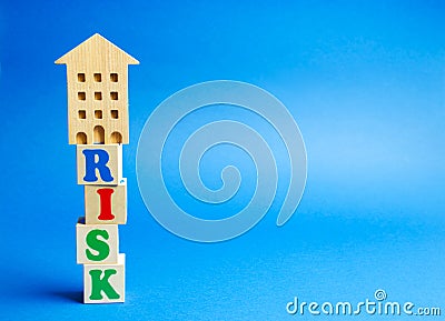 Wooden blocks with the word Risk and a miniature house. Real estate investment risk. Risky investments. Loss of property for non- Stock Photo