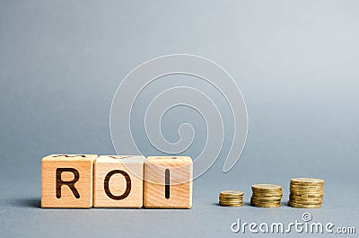 Wooden blocks with the word ROI and coins. High level of business profitability. Return on investment, invested capital, rate. Stock Photo