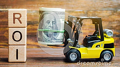 Wooden blocks with the word ROI and money with forklift. Ratio between the net profit and cost of investment resulting from an Stock Photo