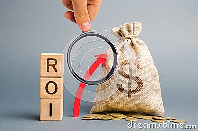 Wooden blocks with the word ROI and the up arrow with the money bag. High level of business profitability. Return on investment, Stock Photo