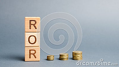 Wooden blocks with the word ROR and coins. High level of business profitability. Return on investment, invested capital, rate. Stock Photo