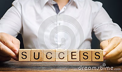 Wooden blocks with the word Success and businessman. Successful business concept. Achieving the goal, overcoming difficulties. The Stock Photo