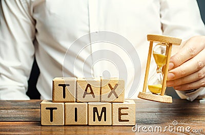 Wooden blocks with the word Tax time and taxpayer with a hourglass. The concept of paying the tax rate. Taxation / burden. Pay off Stock Photo