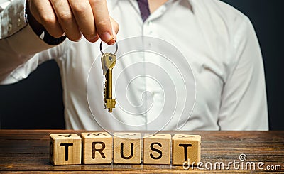 Wooden blocks with the word Trust and keys in the hands of a businessman. Entrust apartment, car, property and real estate. Credit Stock Photo