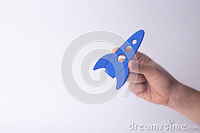 Wooden blue rocket in hand on a white background. A man is playing with a rocket. Minimalism, space travel and tourism, commercial Stock Photo
