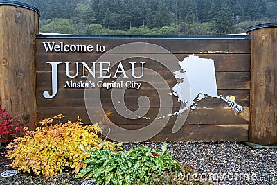 Wooden board sign with text: Welcome to Juneau. Alaska, United States. Editorial Stock Photo