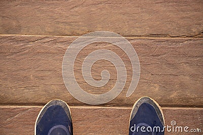 Wooden board top view photo with man feet. Worn male shoes on dusty wooden floor. Rough timber bridge Stock Photo