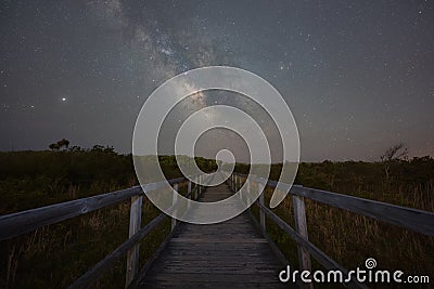 Wooden boardwalk leading towards the stars and the milky way galaxy Stock Photo