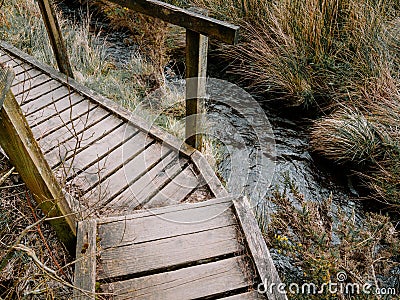 Wooden boardwalk over muddy swampy boggy ground in the UK country side. Stock Photo