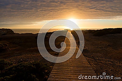 Wooden boardwalk at sunset, coastal landscape Carrapateira West Algarve. cloudy sky Stock Photo