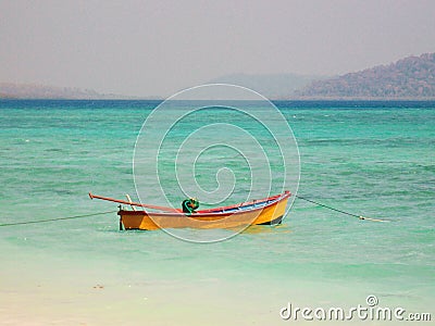 Wooden boat floating on sea at beach light blue beac at Havelock Island Stock Photo