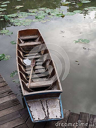 Wooden boat with paddle, parked on the waterfront in the lotus pond Stock Photo