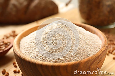 Wooden bowl of buckwheat flour on board Stock Photo