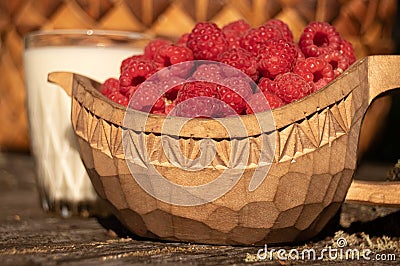 Wooden bowl with fresh ripe rasberries and a glass of milk Stock Photo