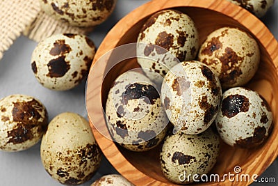 Wooden bowl and many speckled quail eggs on grey table, flat lay Stock Photo