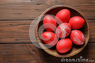 Wooden bowl with painted red Easter eggs on table, top view. Stock Photo