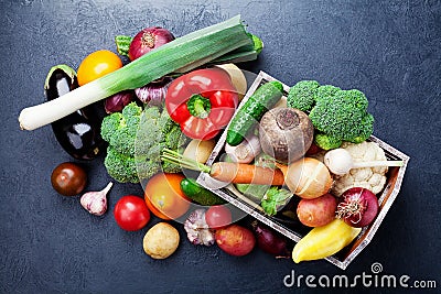 Wooden box with autumn harvest farm vegetables and root crops on black kitchen table top view. Healthy and organic food. Stock Photo