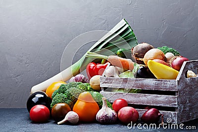 Wooden box with autumn harvest farm vegetables and root crops on dark kitchen table. Healthy and organic food. Stock Photo